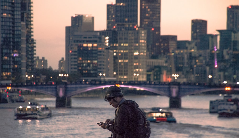 a man standing on a ledge looking at his cell phone