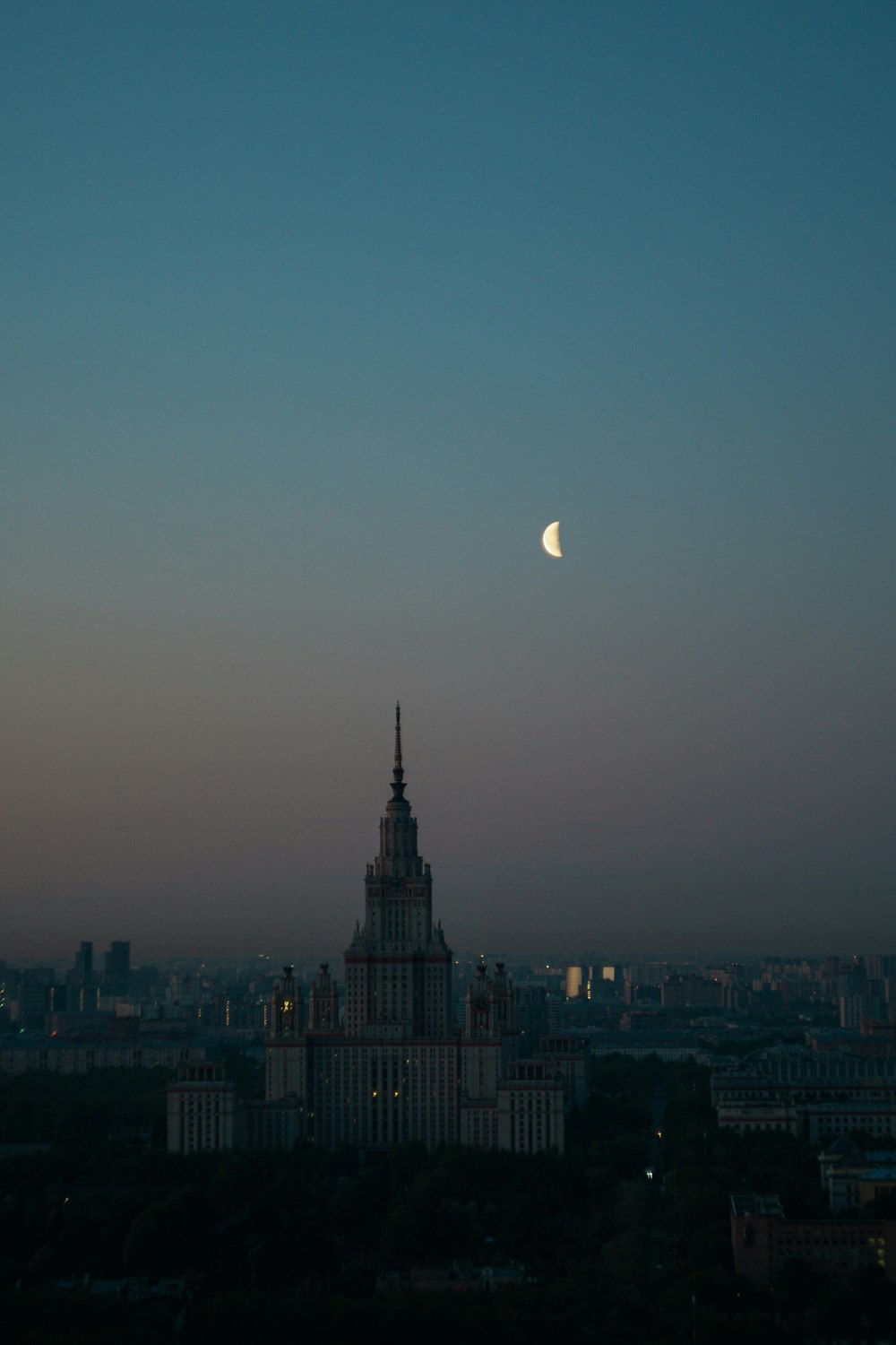 a view of a city with a half moon in the sky