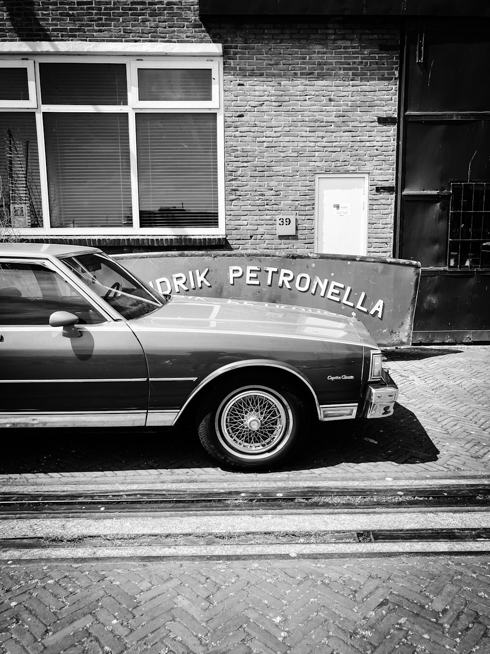 a black and white photo of a car parked in front of a building