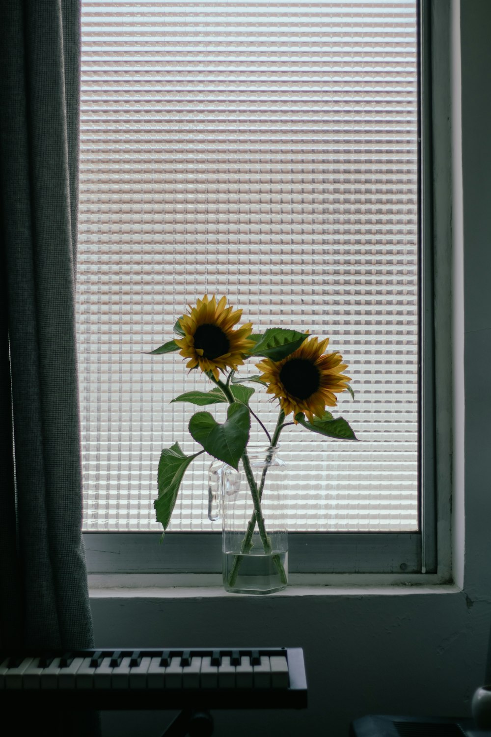 a vase with two sunflowers on a window sill
