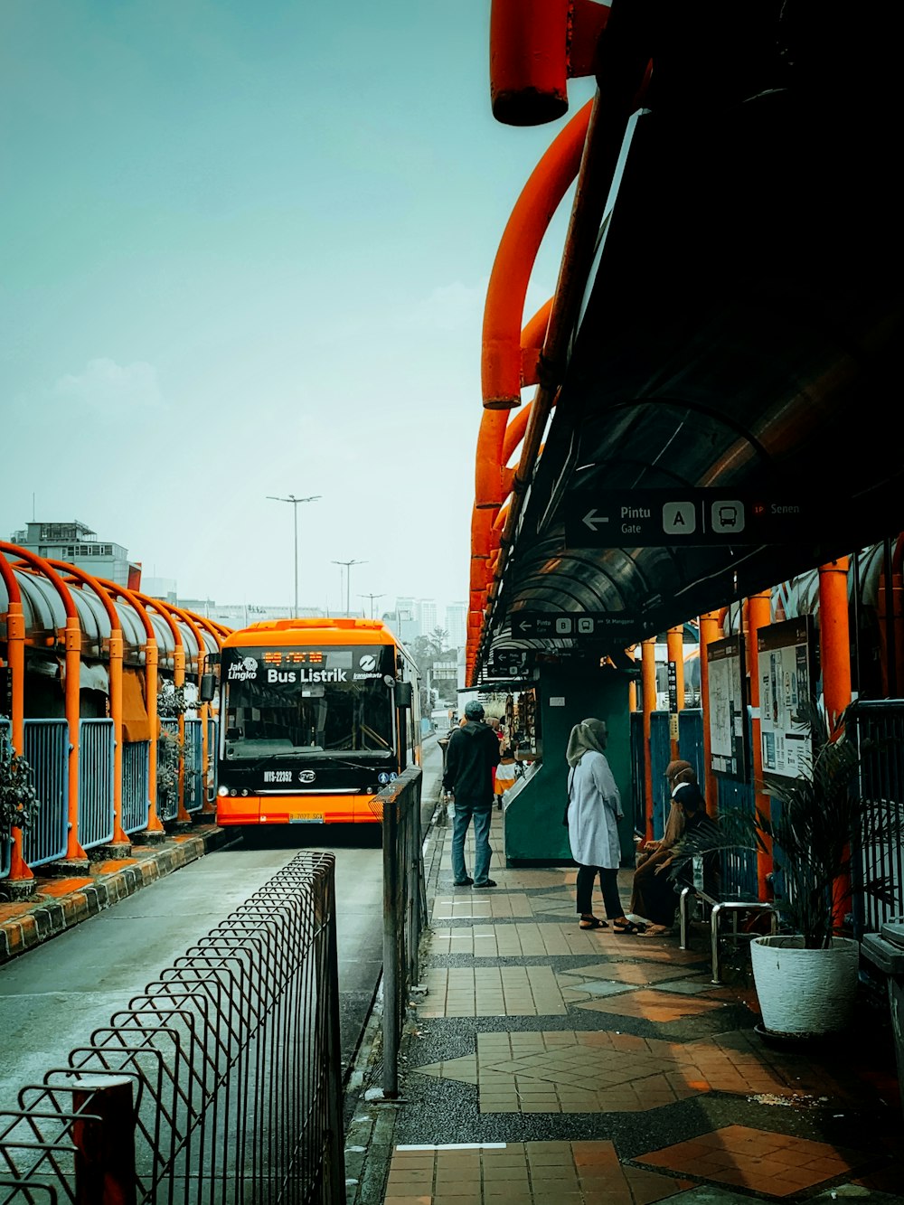 a group of people walking down a sidewalk next to a bus