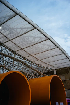 a group of large orange pipes under a canopy