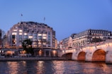 Evening lights reflecting on the water with historic bridges in the background.