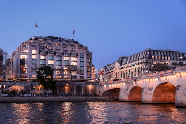 Evening lights reflecting on the water with historic bridges in the background.