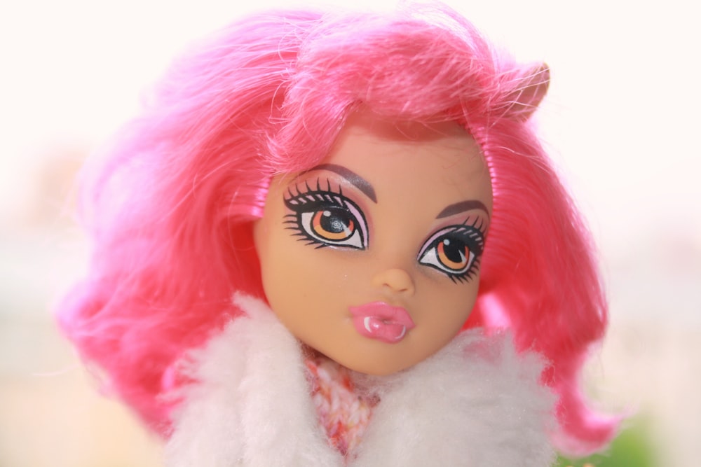 a close up of a doll with pink hair