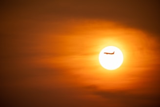 A modern aircraft in flight against a sunset.