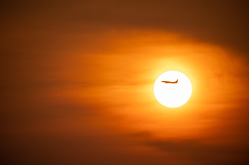 A modern aircraft in flight against a sunset.