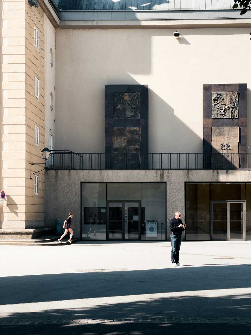 a man walking down a street next to a tall building