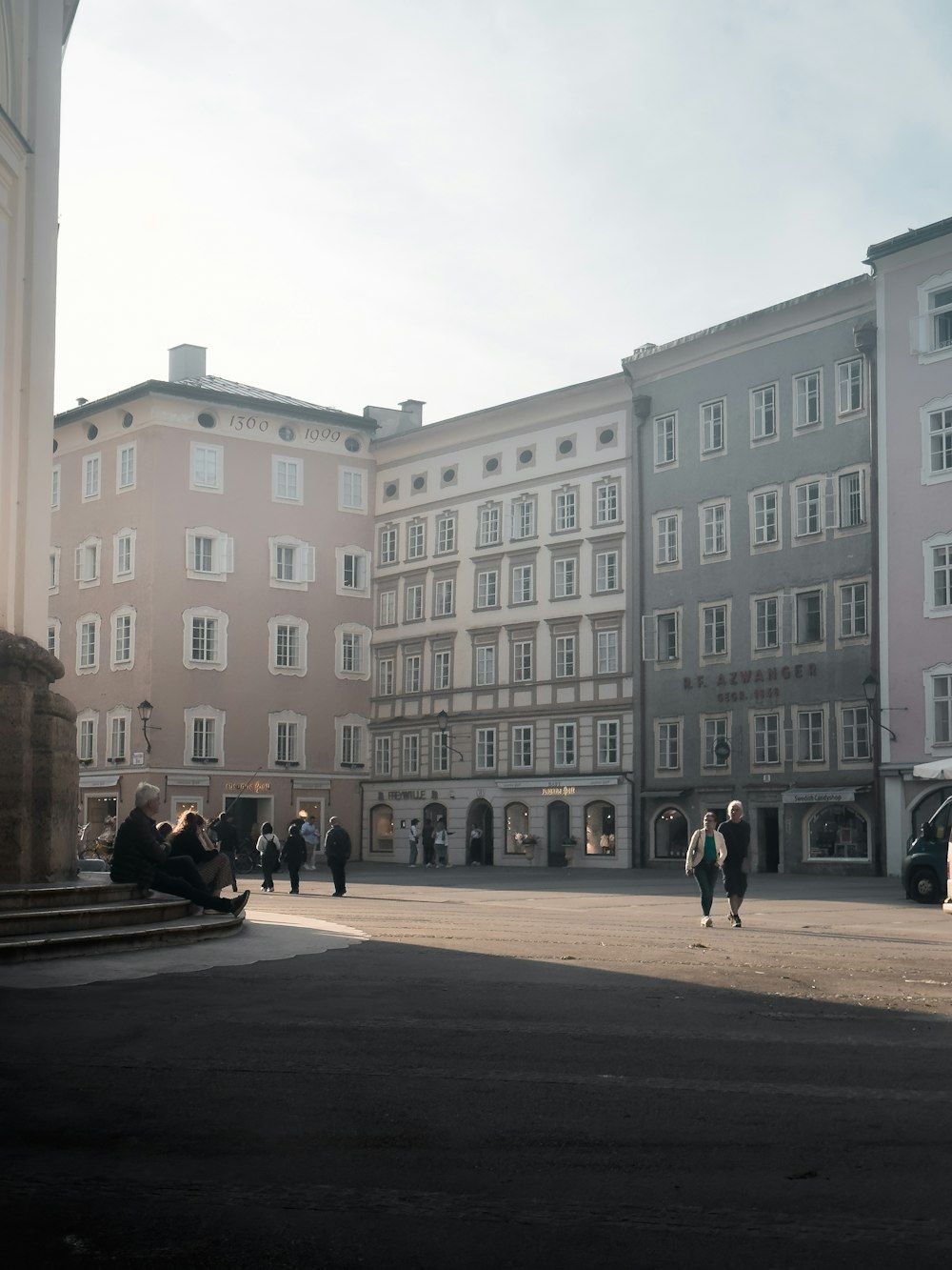 a group of people walking down a street next to tall buildings