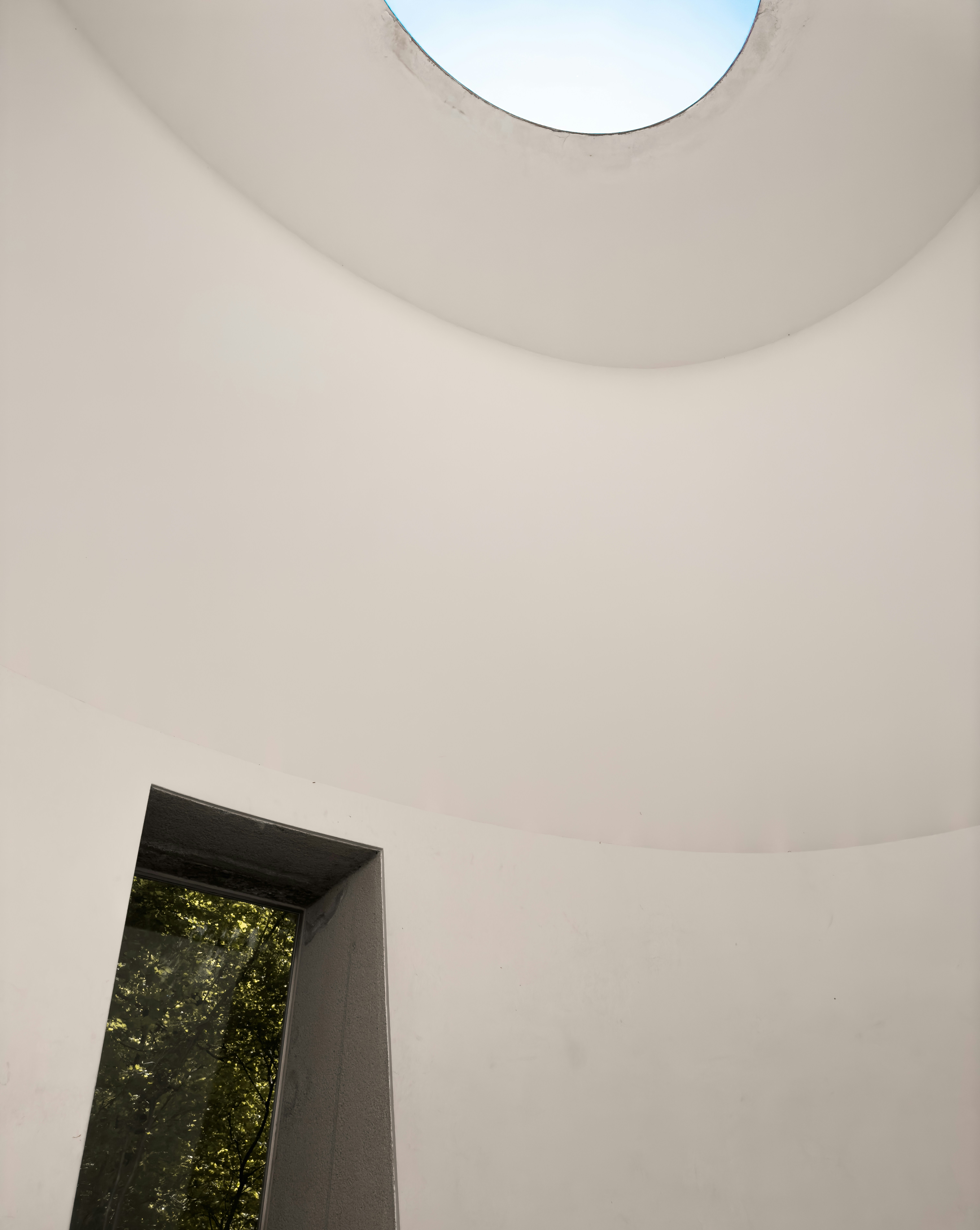 una stanza bianca con una finestra rotonda e un lucernario