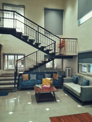 Professional movers carrying a large sofa down a staircase inside a modern home.