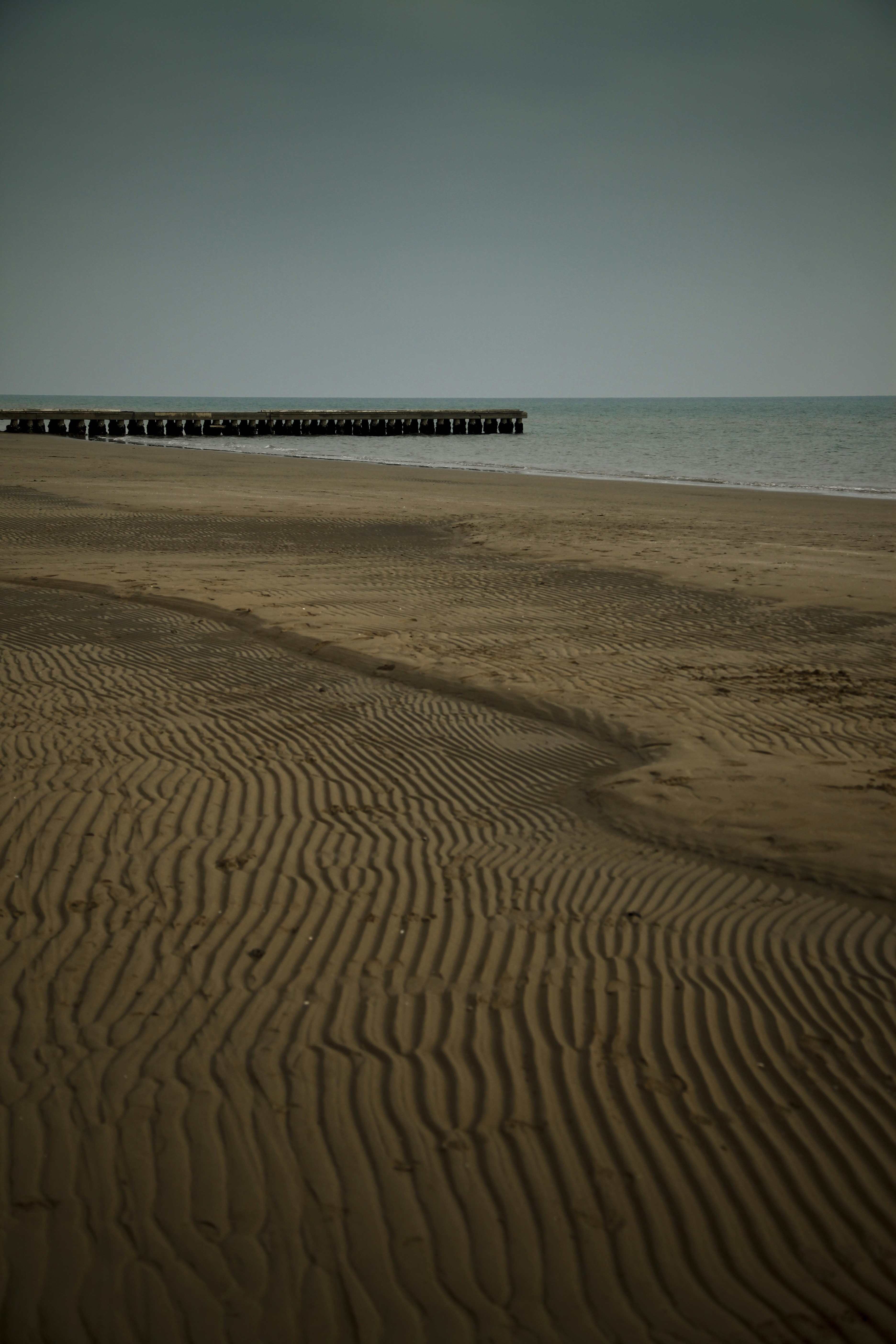 a beach with a pier in the distance