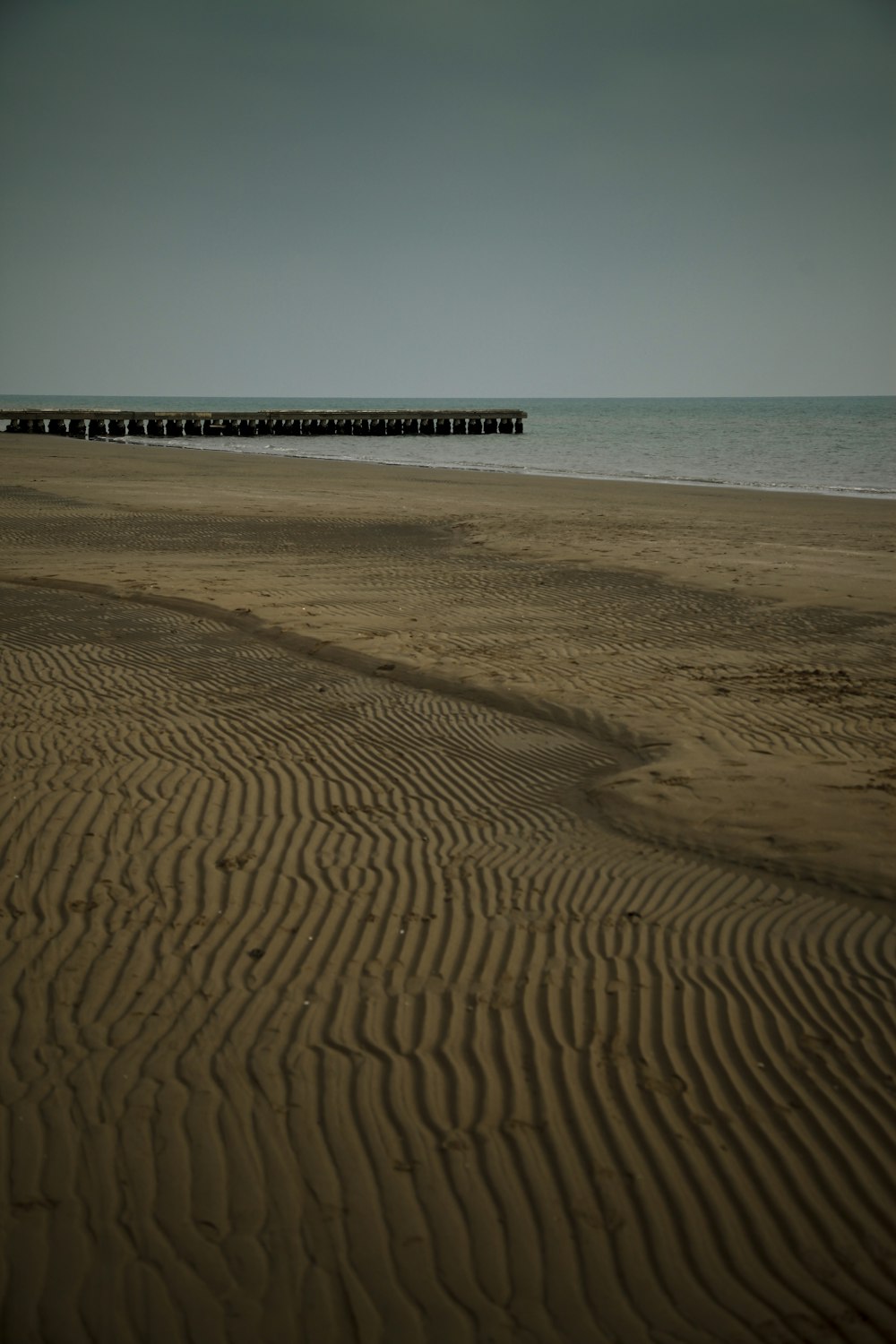 a beach with a pier in the distance