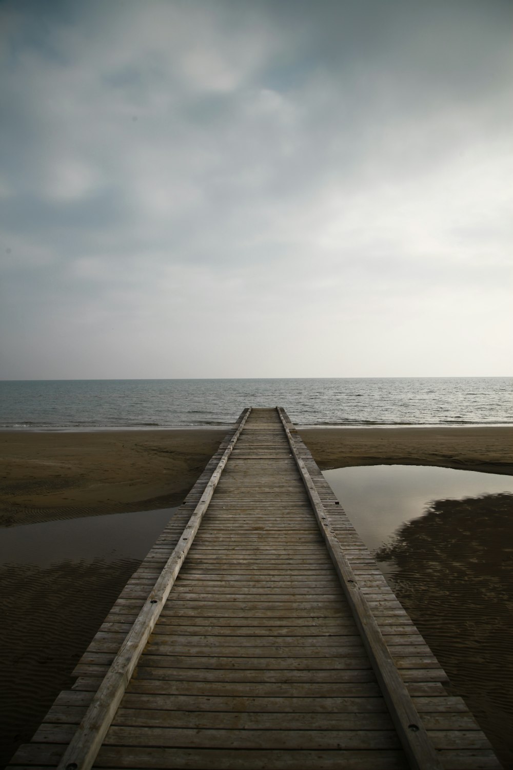 a wooden pier extending into the ocean on a cloudy day