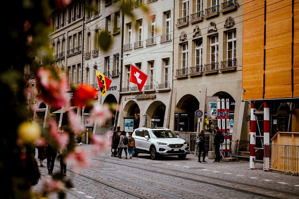 a white car driving down a street next to tall buildings