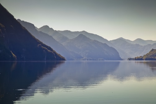 A serene lake reflecting the surrounding mountains during a calm summer evening.