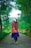 a woman with long hair walking down a dirt road