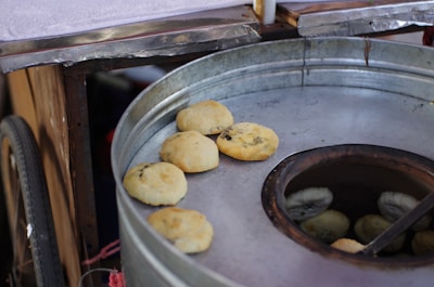 Freshly baked naan bread coming out of the traditional tandoor oven, with visible char marks.