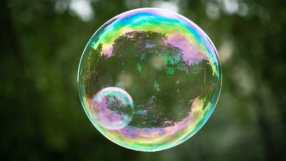 a soap bubble floating in the air with trees in the background