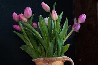 A vibrant bouquet of freshly cut tulips in soft pastel shades, arranged in a rustic ceramic vase.