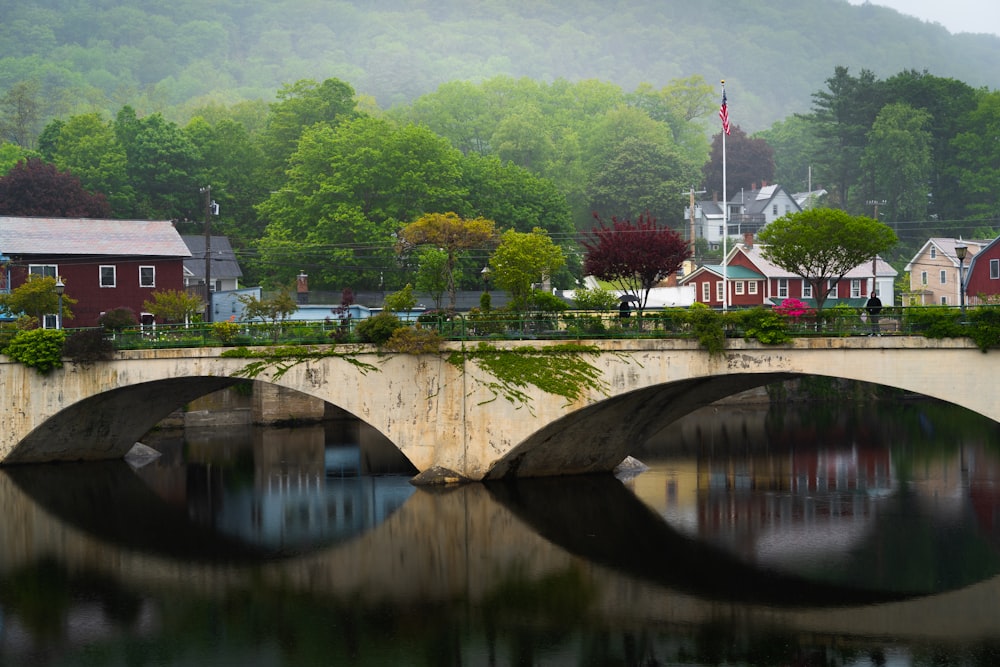 a bridge over a body of water with houses in the background