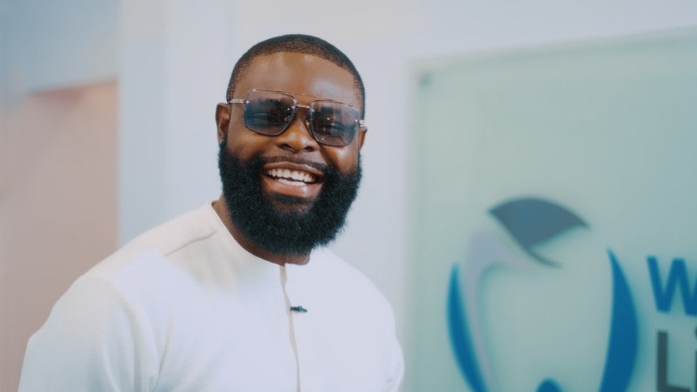 a man with a beard and sunglasses standing in front of a sign