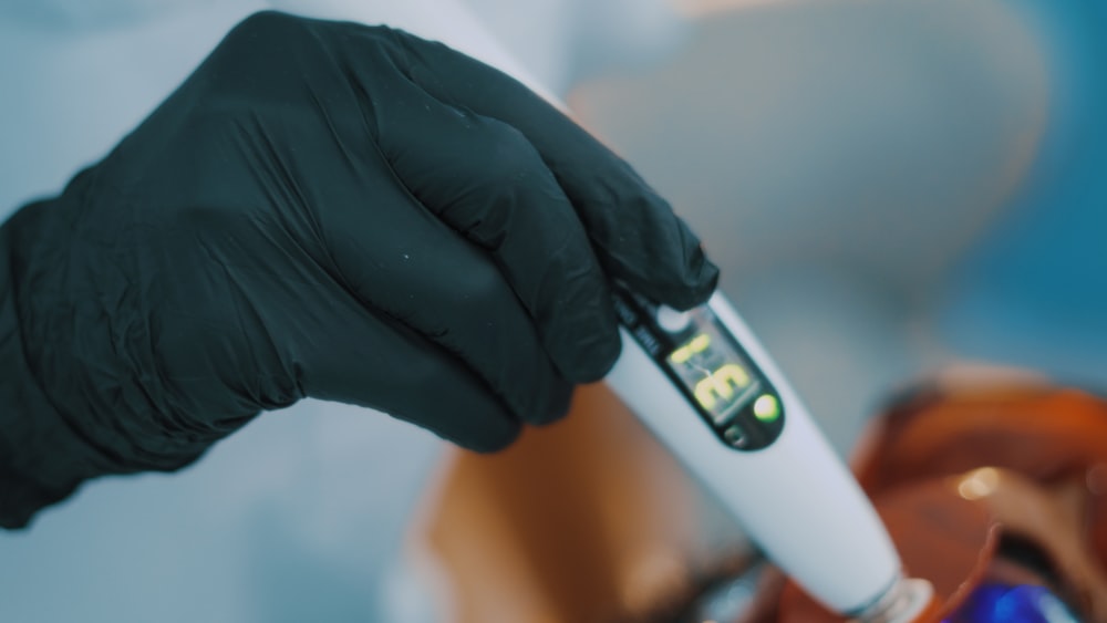 a person in black gloves and gloves holding a toothbrush