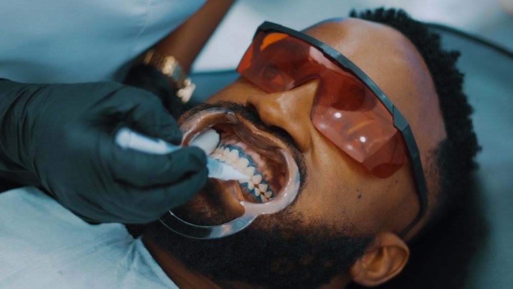 um homem recebendo seus dentes escovados por um dentista