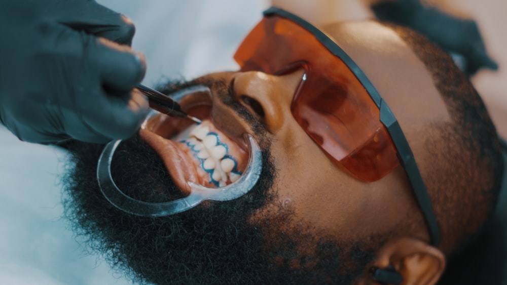 a man getting his teeth brushed by a dentist