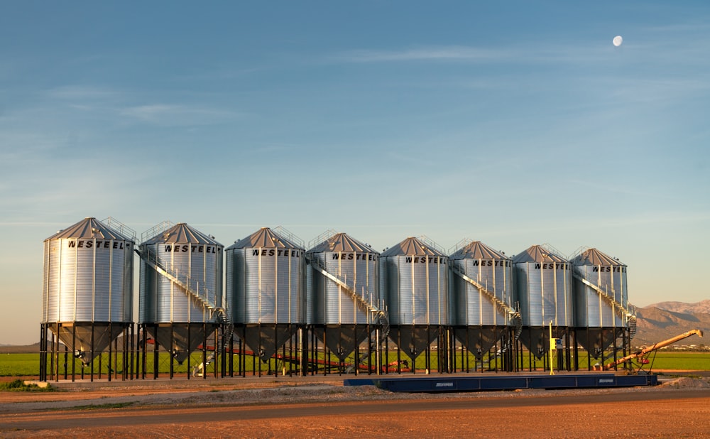 a row of metal silos sitting on top of a dirt field