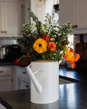A bright, ergonomic watering can placed among blooming flowers.