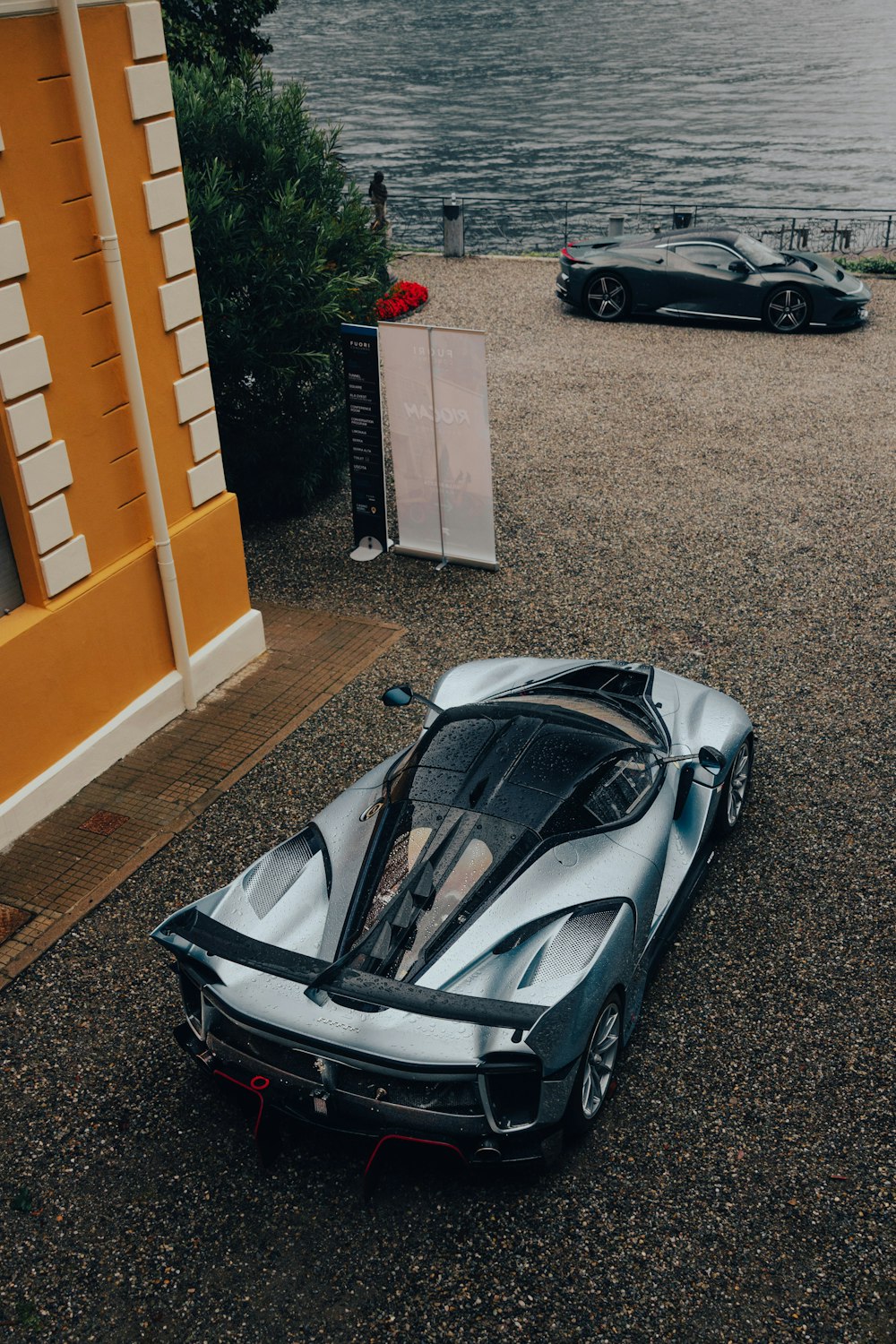 a silver and black sports car parked next to a body of water