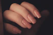 Close-up of freshly painted bright red nails with glitter accents on a cozy cafe table