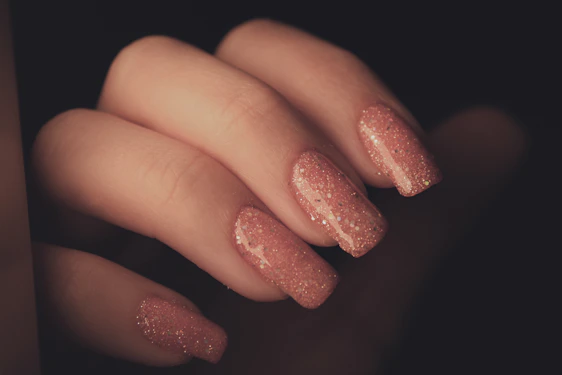 Close-up of hands showcasing glossy neon pink and purple gel X nails under soft lighting.