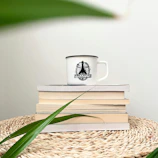 Cozy lifestyle scene featuring a stylish ceramic mug beside a stack of books and a plant.