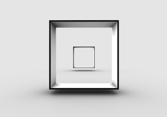 A minimalist 3D rendering of a cube-shaped frame suspended in a stark gray environment. Within the larger frame, a smaller, identical frame is positioned centrally, creating a sense of depth and recursion.
