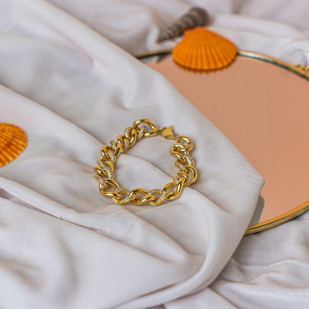 a gold chain bracelet laying on top of a white blanket