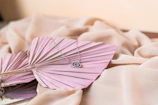 Delicate rose gold necklace with floral motifs displayed on vintage beige fabric.