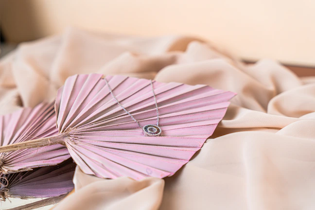 A beautifully wrapped personalized necklace resting on soft pastel fabric.