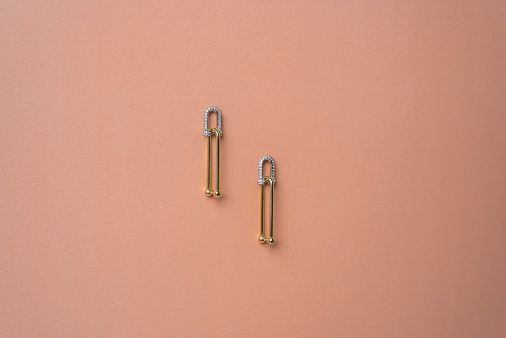 a pair of gold and diamond earrings on a pink background
