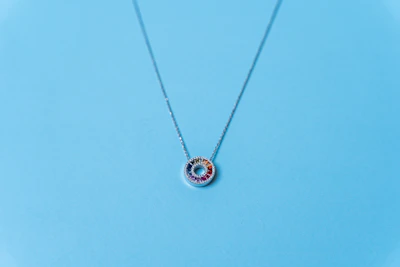 A delicate gold necklace featuring a sparkling fine zircon pendant against a deep navy blue background.
