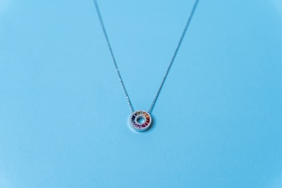 Elegant necklace with multicolored gem-like stones displayed against a bright, textured background.