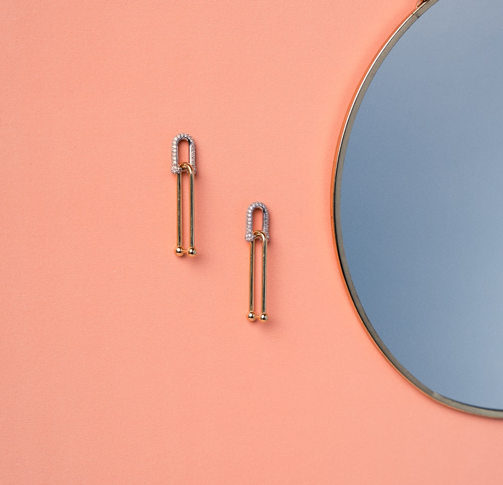 a pair of earrings sitting next to a mirror