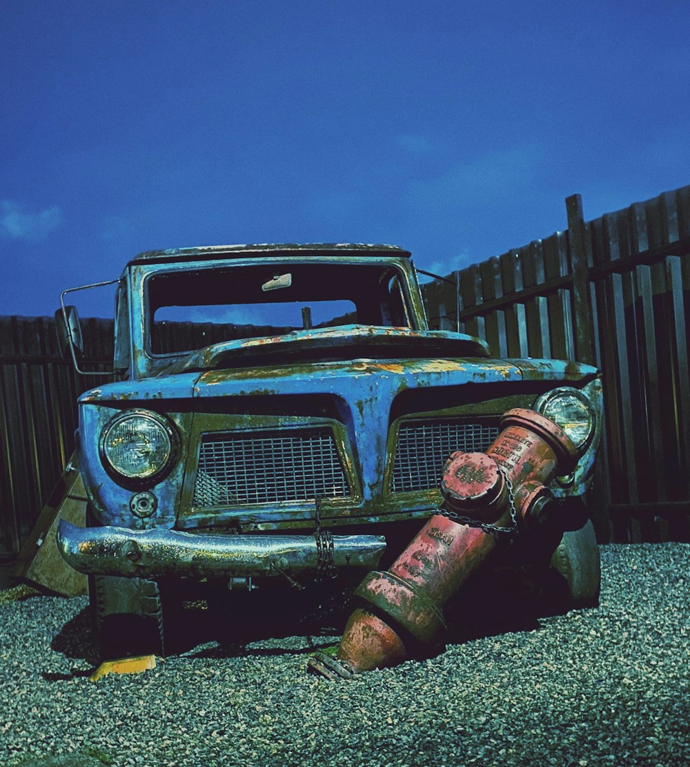 a rusted old truck sitting in a gravel lot