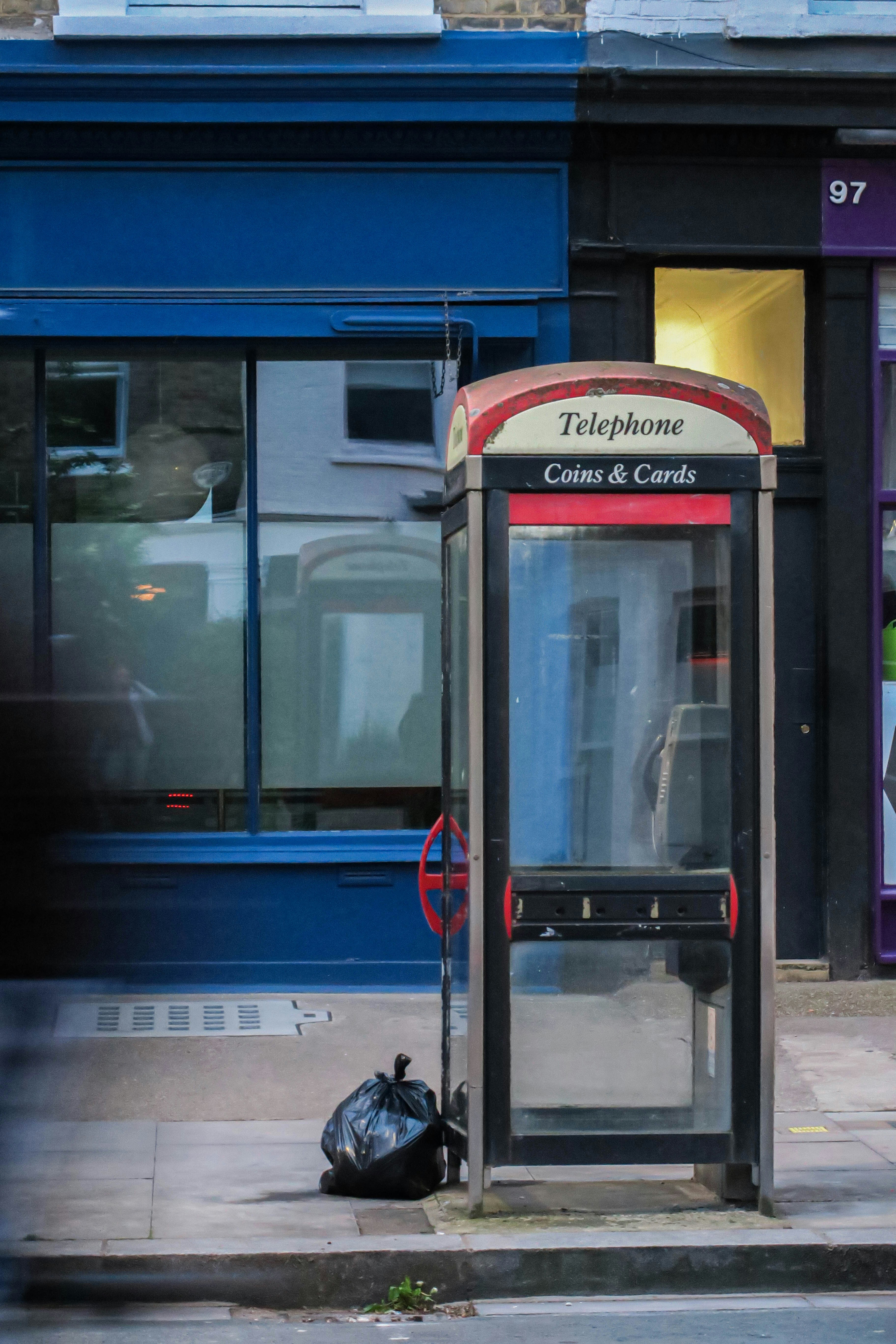 a public phone booth sitting on the side of a street