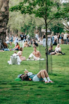Young adults happily using apps on their phones in a sunny park setting.