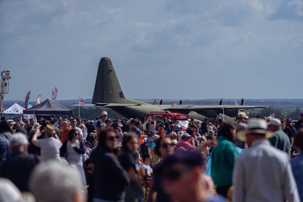 Una multitud de personas de pie alrededor de un avión militar