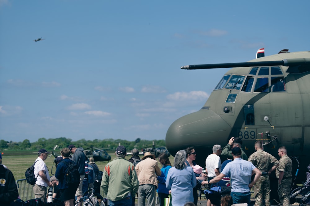 um grupo de pessoas em pé ao redor de um avião militar