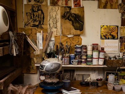 Artist's workspace filled with paints, sketches, and custom vinyl toys in progress.