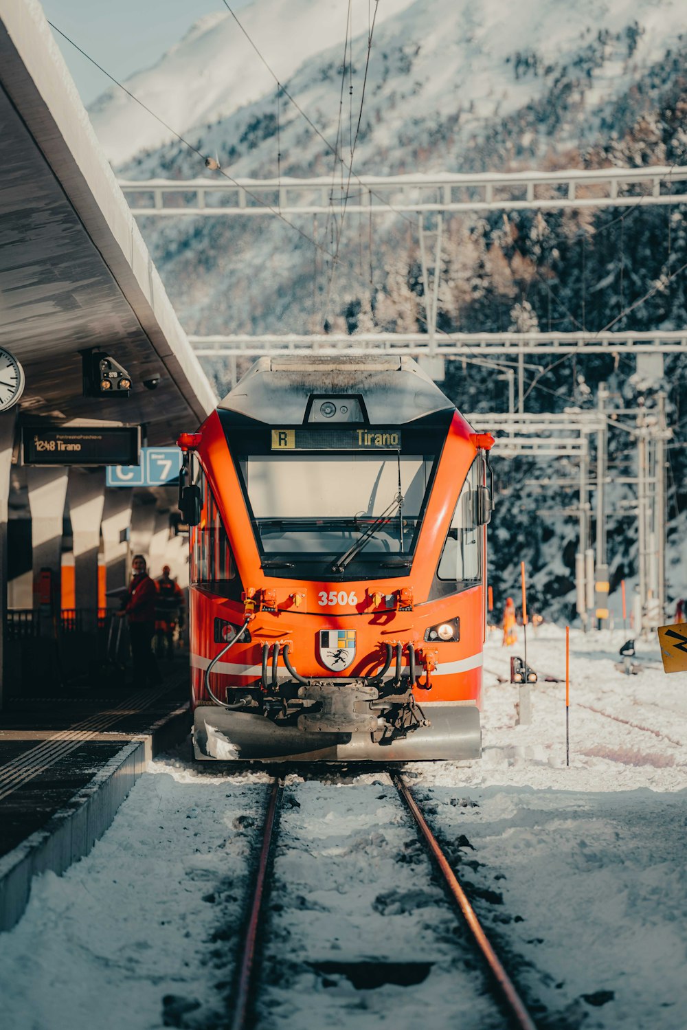 an orange train pulling into a train station